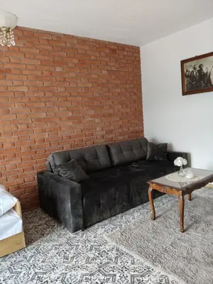 a black leather couch in a living room with a brick wall at Słoneczne apartamenty Zator blisko Energylandii in Zator