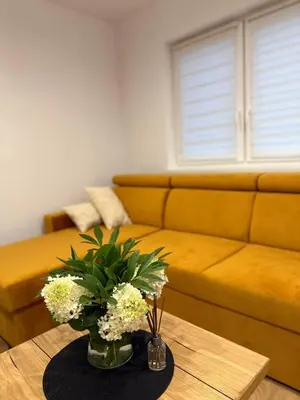 a living room with a couch and a table with flowers at Zator Domki Dreampark in Zator
