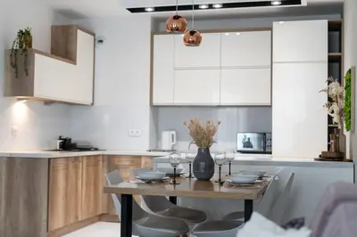 a kitchen with a wooden table and white cabinets at Malila Premium Apartments Cracow Cystersów 20D in Kraków