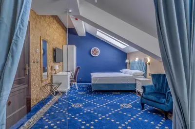 a blue room with a bed and a chair at Czeczotka Palace Apartments in Kraków