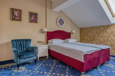 a bedroom with a large bed and a blue chair at Czeczotka Palace Apartments in Kraków