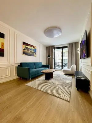 a living room with a table and a blue couch at The Velvet Apartment Kościuszki in Kraków