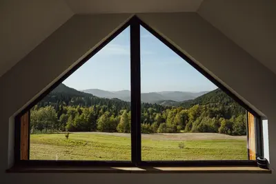 a window with a view of a field and mountains at Polana Kasztelana - Beskid Wyspowy in Limanowa