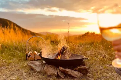 a person holding a glass of wine next to a fire at Polana Kasztelana - Beskid Wyspowy in Limanowa
