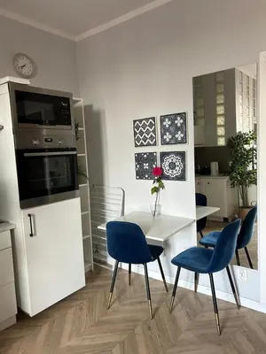 a kitchen with a white table and blue chairs at Nowy Kleparz Apt in Kraków