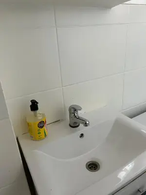 a white sink with a bottle of soap on it at Nowy Kleparz Apt in Kraków