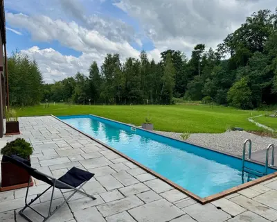 a swimming pool with a chair and a lawn at Jaśminowa Pracownia in Rupniów