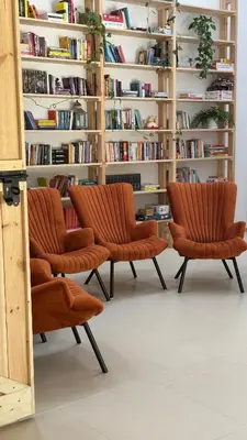 three orange chairs in front of a book shelf at Jaśminowa Pracownia in Rupniów