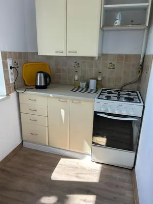 a kitchen with a stove and white cabinets at Hala Targowa Apartament in Kraków