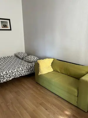 a living room with a green couch and a bed at Hala Targowa Apartament in Kraków