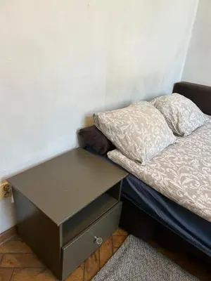 a small bed with a nightstand next to a wall at Planty Apartament in Kraków