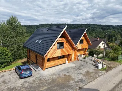 a log cabin with a car parked in front of it at Chałpy H700 in Koszarawa