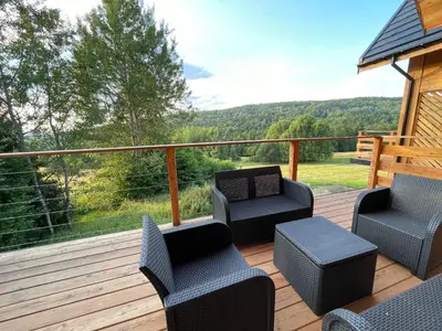 a deck with chairs and tables and a view of the mountains at Chałpy H700 in Koszarawa