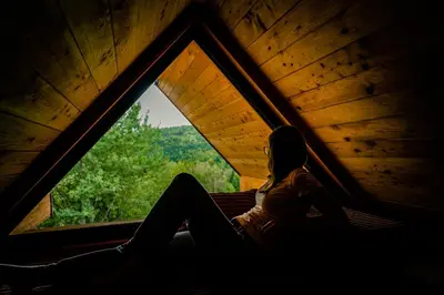 a woman sitting in a tent looking out a window at Chałpy H700 in Koszarawa