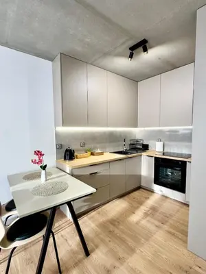 a kitchen with white cabinets and a table and chairs at Piast Apartment - free parking in Kraków