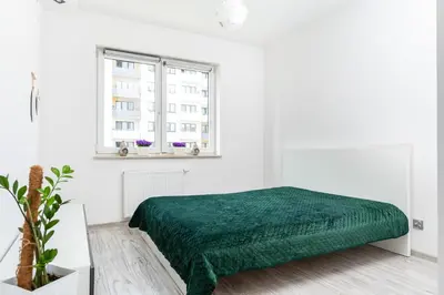 a white bedroom with a green bed and a window at Apartament Bonarka-Podgórze in Kraków