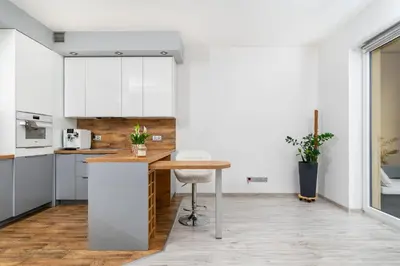 a kitchen with white cabinets and a wooden table at Apartament Bonarka-Podgórze in Kraków