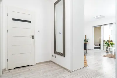 a white door in a white room with a mirror at Apartament Bonarka-Podgórze in Kraków