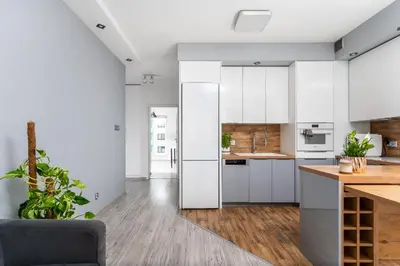 a kitchen with white cabinets and a gray chair at Apartament Bonarka-Podgórze in Kraków