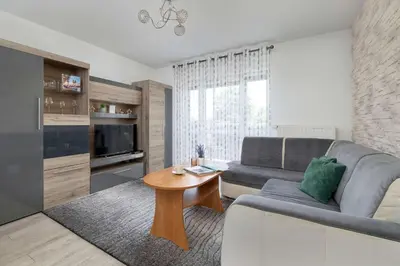 a living room with a couch and a table at Modern Apartment with a Balcony in a Quiet Estate by Noclegi Renters in Kraków