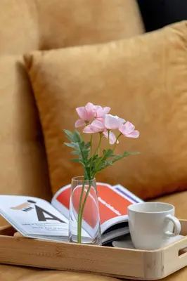 a vase with pink flowers on a tray with a cup at Modern Apartment with a Balcony in a Quiet Estate by Noclegi Renters in Kraków