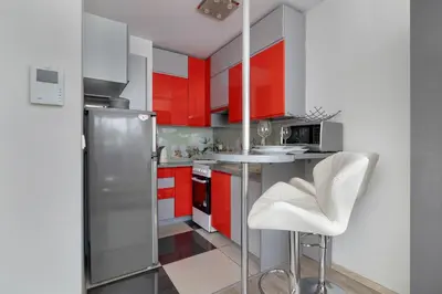 a kitchen with red cabinets and a counter with a stool at Modern Apartment with a Balcony in a Quiet Estate by Noclegi Renters in Kraków