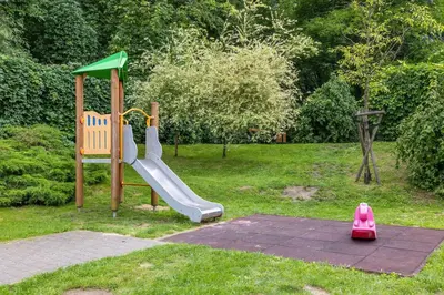 a playground with a slide in the grass at Modern Apartment with a Balcony in a Quiet Estate by Noclegi Renters in Kraków