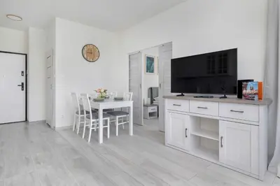 a white living room with a table and a flat screen tv at Bright Apartment in Cracow Center with Terrace, Desk and Bathtub by Noclegi Renters in Kraków