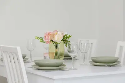 a table with plates and glasses and a vase with flowers at Bright Apartment in Cracow Center with Terrace, Desk and Bathtub by Noclegi Renters in Kraków