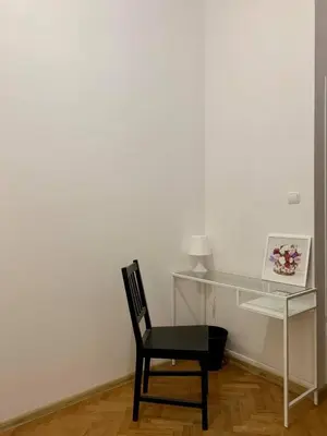 a black chair sitting in front of a white wall at Enios Rooms ul Jana kochanowskiego 26 in Kraków
