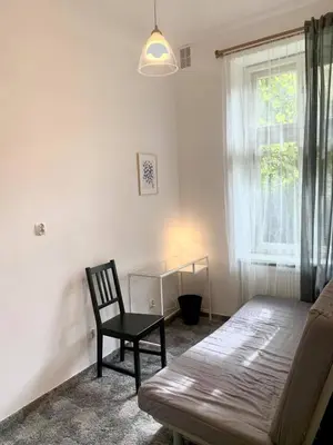 a bedroom with a couch and a chair and a window at Enios Rooms ul Jana kochanowskiego 26 in Kraków