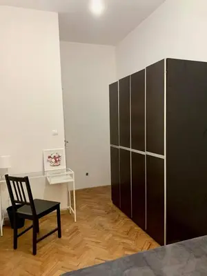 a room with a black cabinet and a chair at Enios Rooms ul Jana kochanowskiego 26 in Kraków