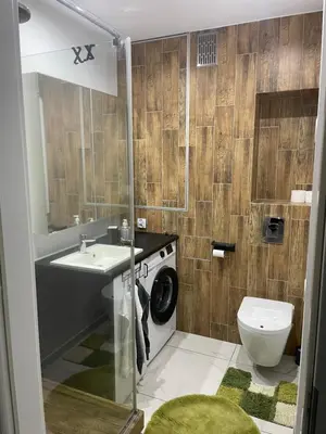 a bathroom with a toilet sink and a washing machine at Monte Cassino Apartament in Oświęcim