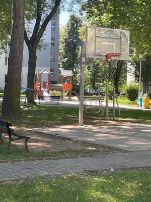 a basketball hoop in a park with a bench at Monte Cassino Apartament in Oświęcim