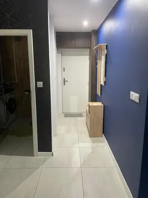 a hallway with a blue wall and a door at Monte Cassino Apartament in Oświęcim