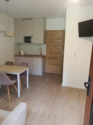 a living room with a table and a kitchen at Domki na Górkach in Spytkowice