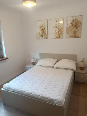 a white bed in a bedroom with three pictures on the wall at Domki na Górkach in Spytkowice