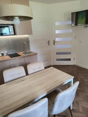 a kitchen with a wooden table and white chairs at Domki na Górkach in Spytkowice