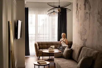 a woman sitting on a couch in a living room at Old Town Kraków by Downtown Apartments in Kraków