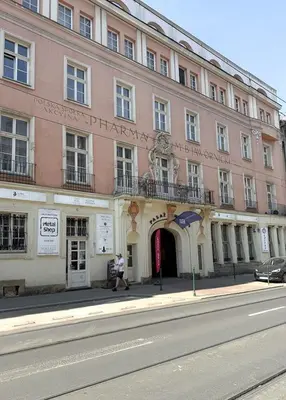 a person walking in front of a pink building at Old Town Kraków by Downtown Apartments in Kraków