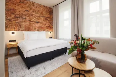a bedroom with a bed and a brick wall at Nomadic Lite in Kraków
