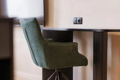 a green chair sitting in front of a table at Nomadic Lite in Kraków