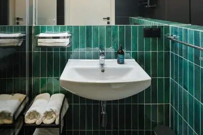 a white sink in a green tiled bathroom at Nomadic Lite in Kraków