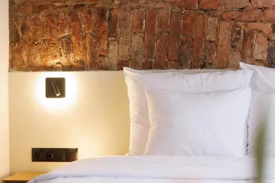 a bed with white pillows and a brick wall at Nomadic Lite in Kraków