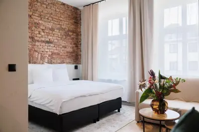 a bedroom with a bed and a brick wall at Nomadic Lite in Kraków