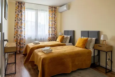 a bedroom with two beds with yellow sheets and a window at Apartament Orawska U Pana Cogito in Kraków
