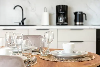 a wooden table with plates and wine glasses on it at Apartament Orawska U Pana Cogito in Kraków