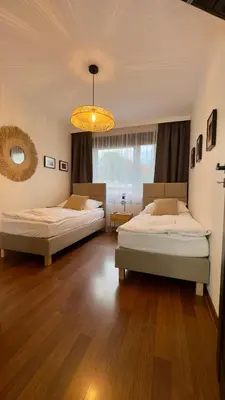 a bedroom with two beds and a chandelier at Apartamenty Oracka Przystań Solna 2 in Bochnia
