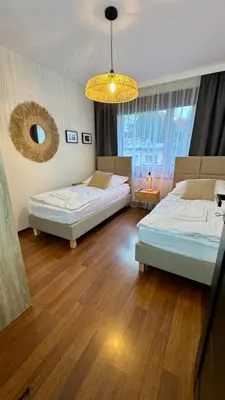 a bedroom with two beds and a chandelier at Apartamenty Oracka Przystań Solna 2 in Bochnia