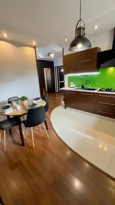 a kitchen with a table and chairs and a green wall at Apartamenty Oracka Przystań Solna 2 in Bochnia